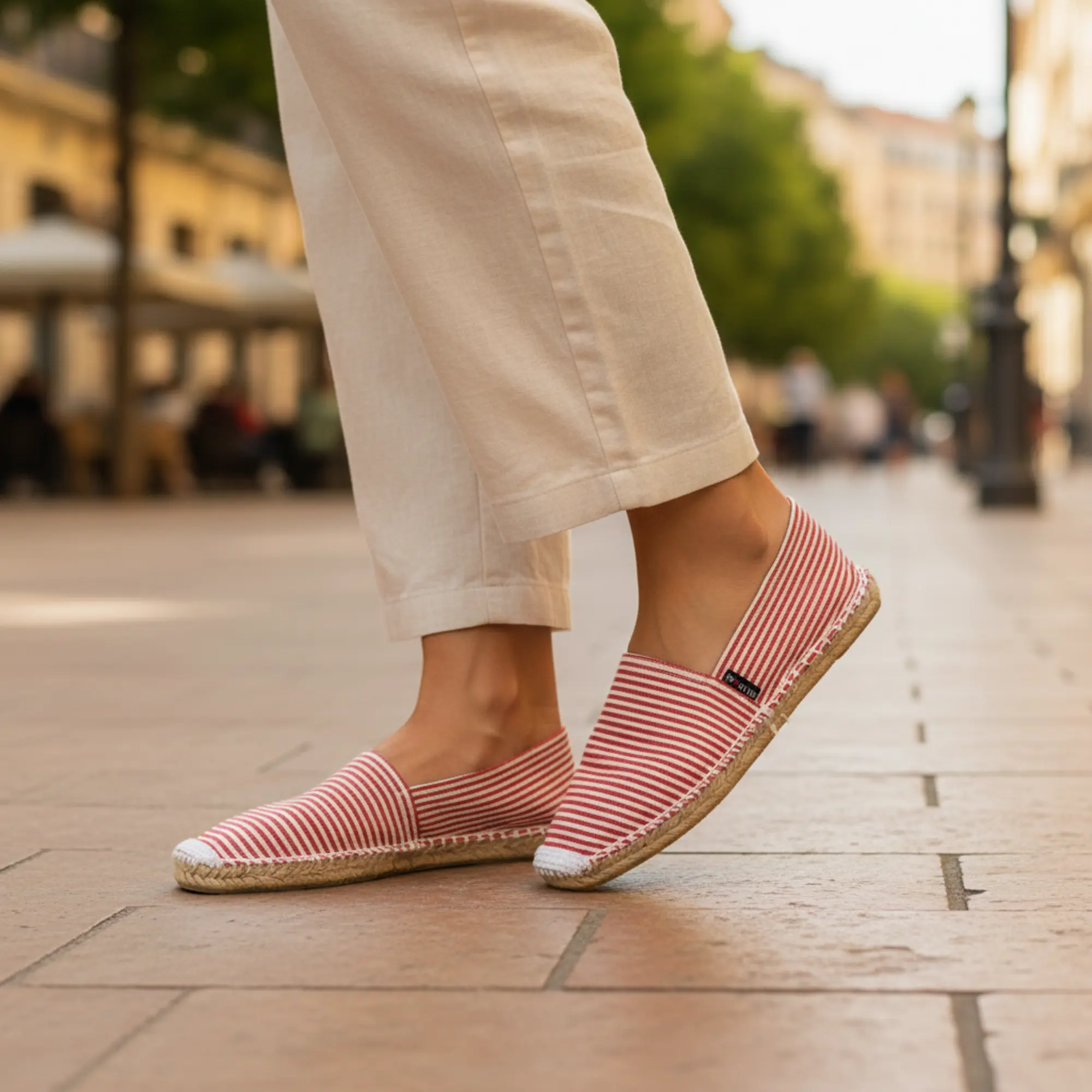 Espadrilles mit rotem Streifen auf dem Bürgersteig in der Fußgängerzone.