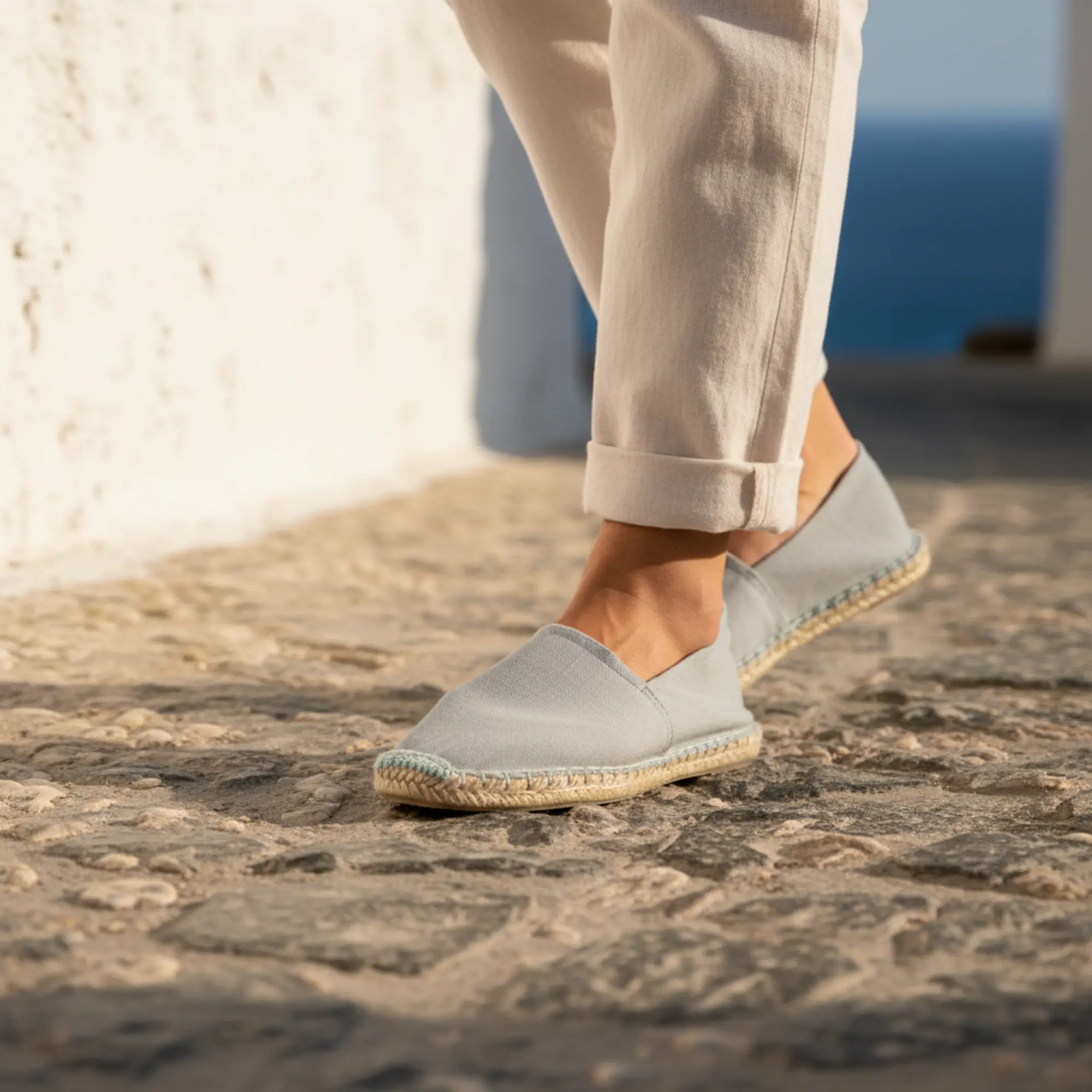 Graue Espadrilles, weiße Hose, Person geht draußen.