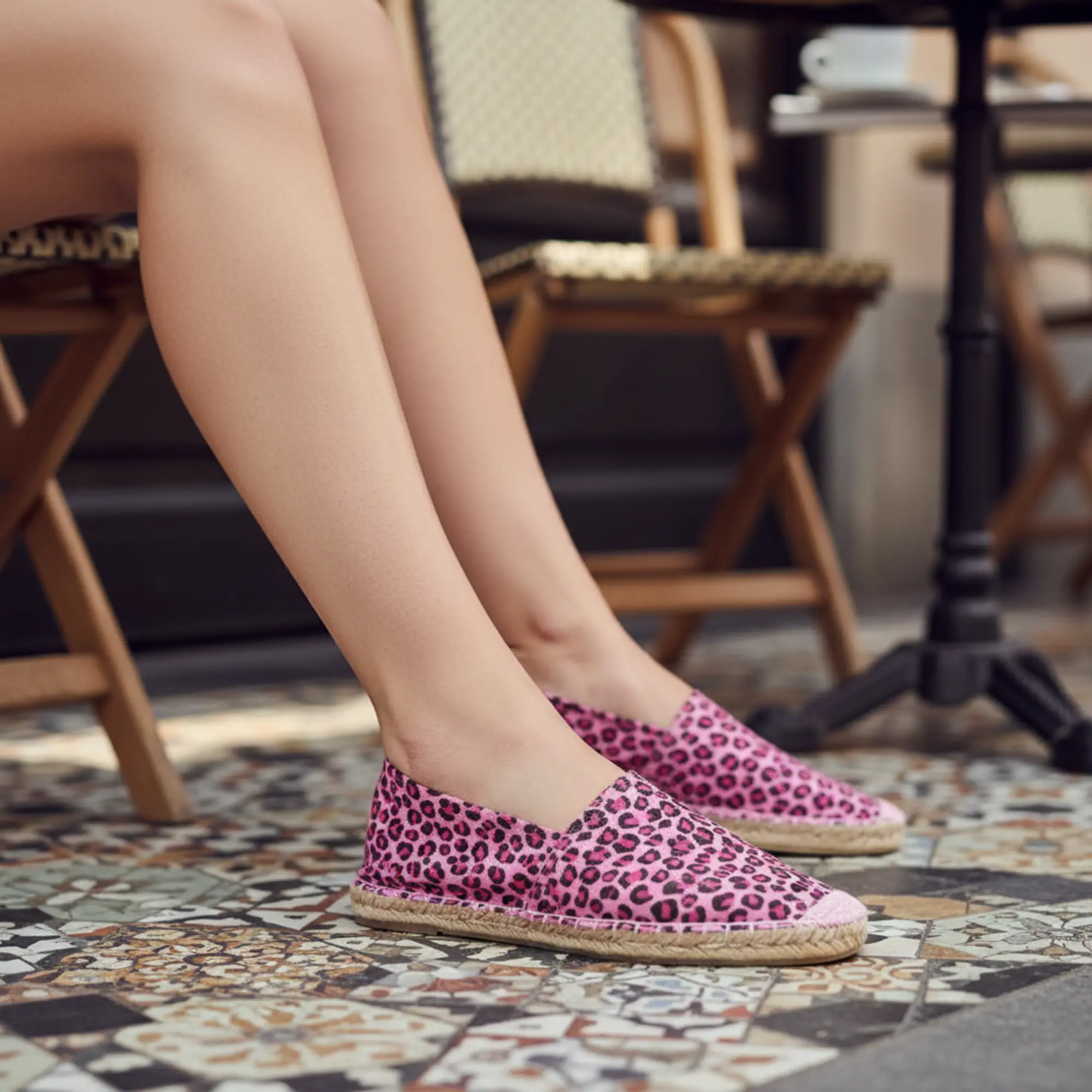 Pinkfarbene Espadrilles mit Leopardenmuster auf gefliester Terrasse.