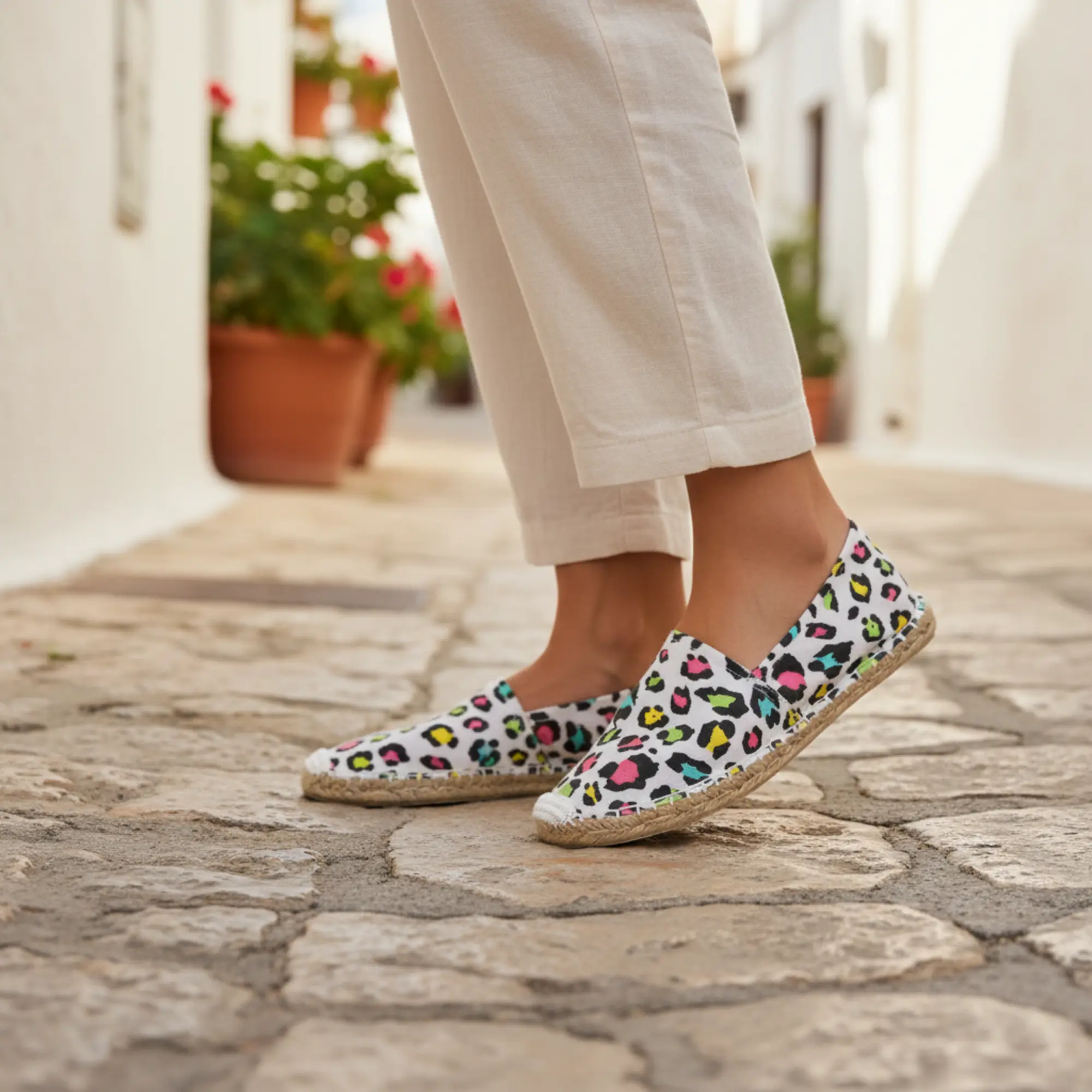 Person mit weißen, bunten Espadrilles mit Leopardenmuster auf dem Weg.
