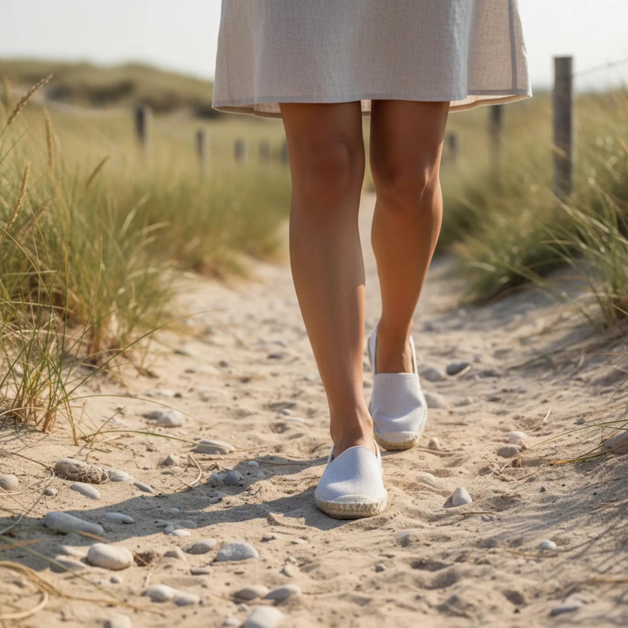 Weiße Espadrilles auf dem sandigen Strandweg.