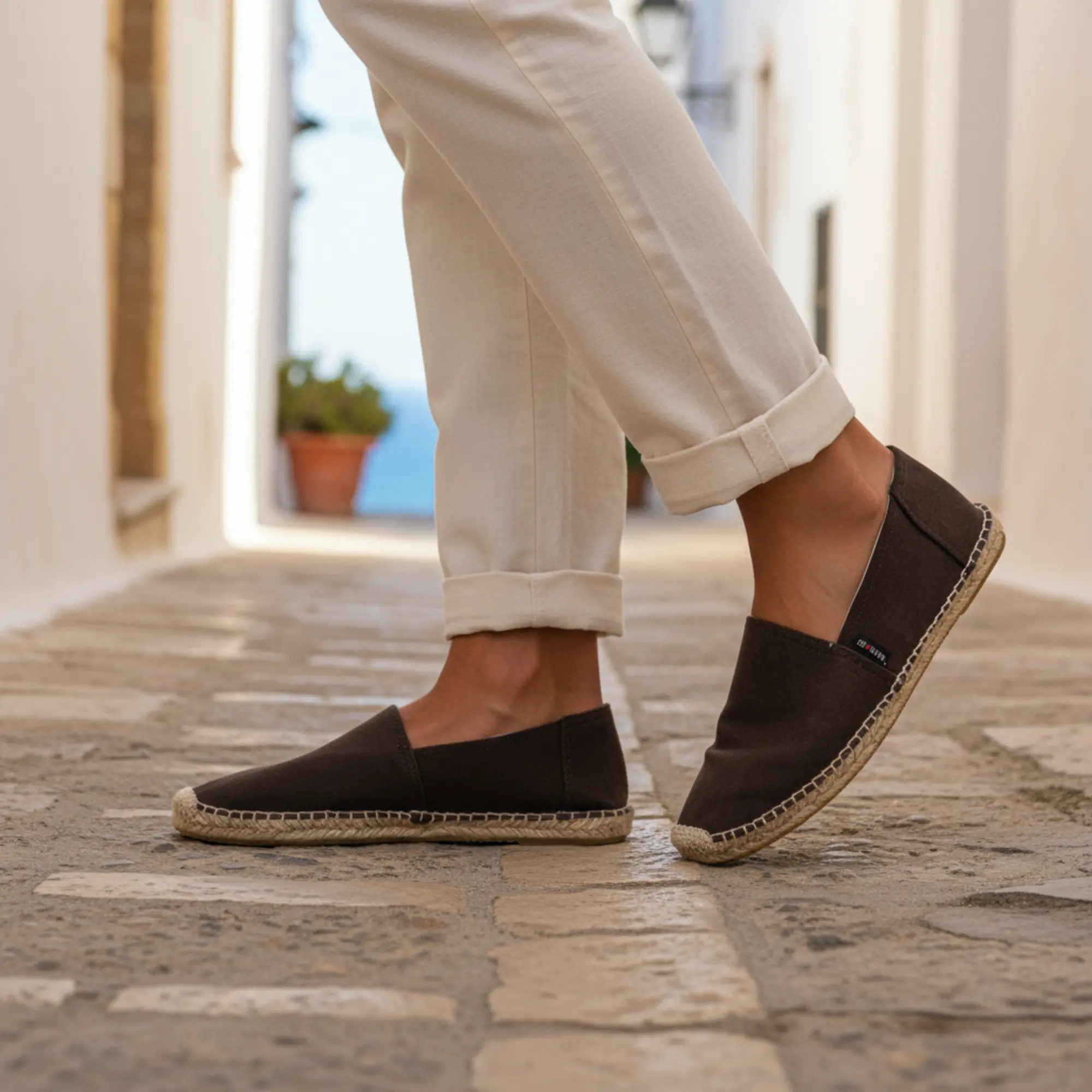 Braune Rauleder-Espadrilles auf einer Kopfsteinpflasterstraße.