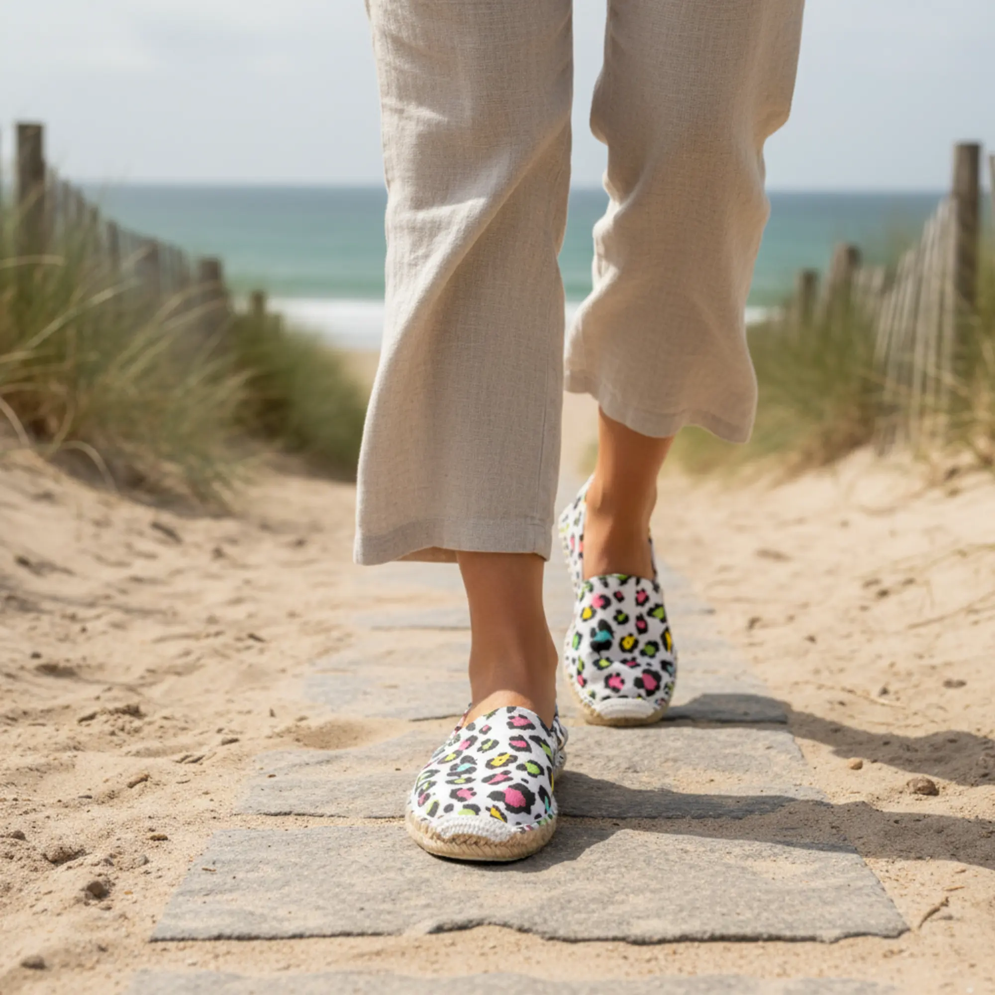 Frau geht auf einem Sandweg in Leoparden-Espadrilles.