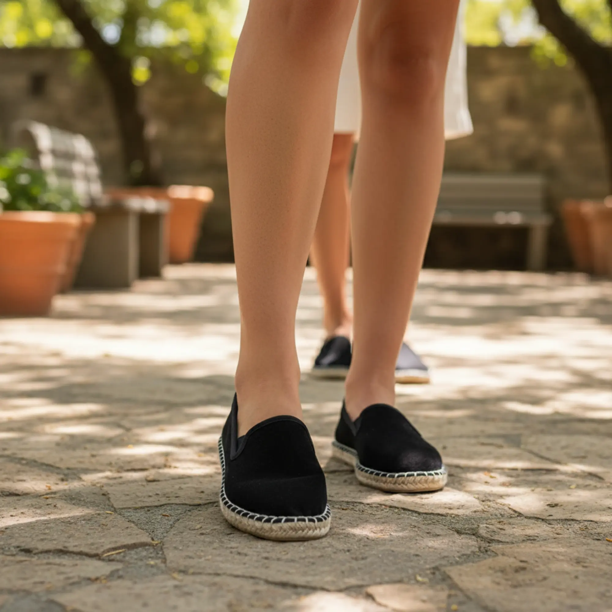 Frau mit schwarzen Espadrilles im Garten.