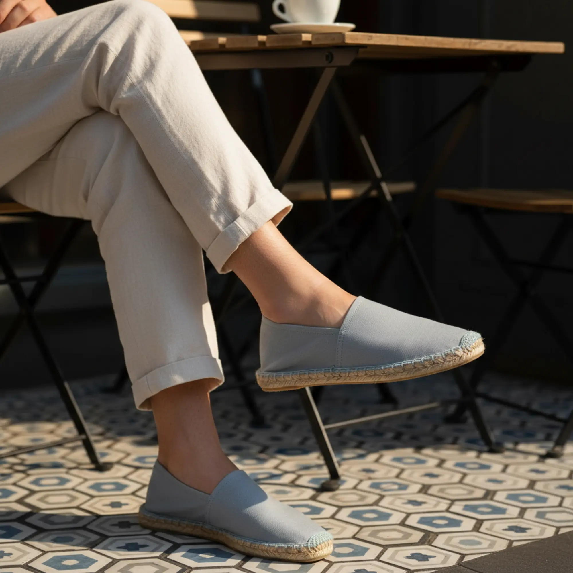 Espadrilles in Hellgrau an den Füßen der Person im Freien.