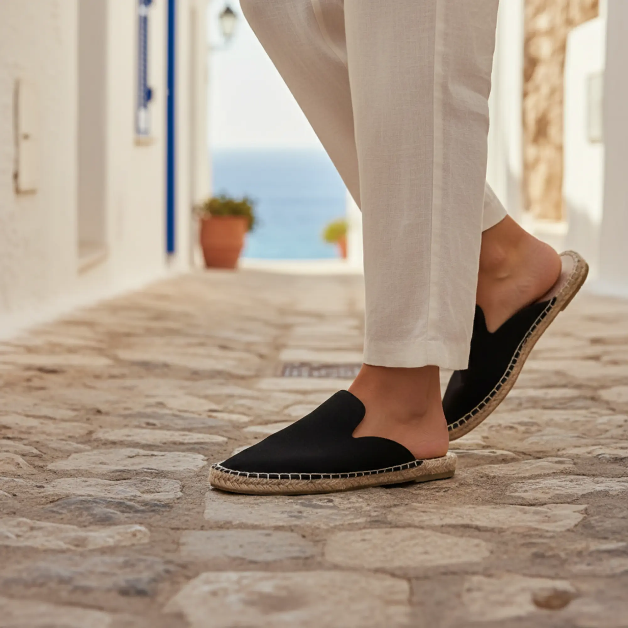 Schwarze Espadrilles aus Segeltuch für einen Spaziergang auf einem sonnigen Steinweg.
