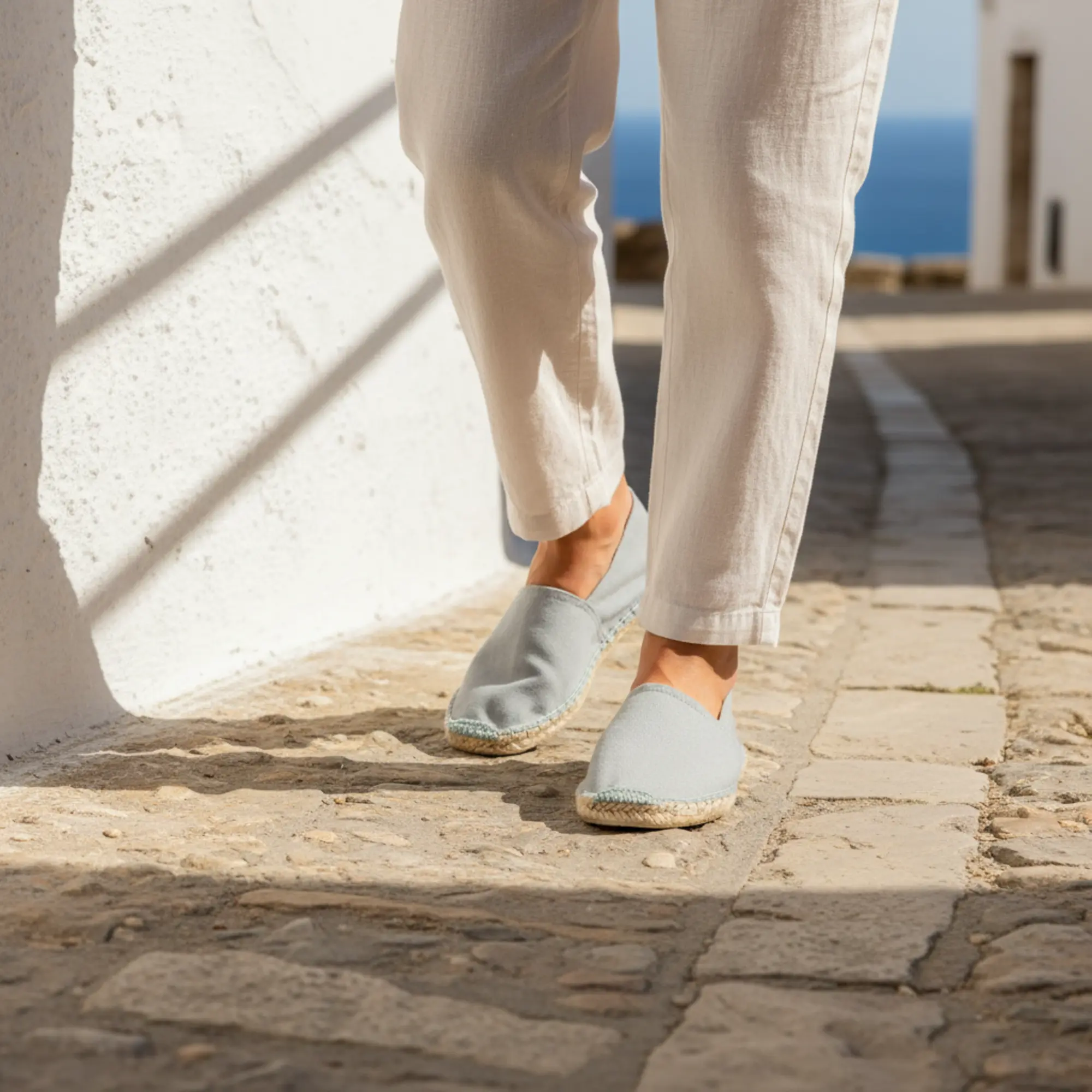 Blaue Espadrilles auf Kopfsteinpflasterstraße, Leinenhosen