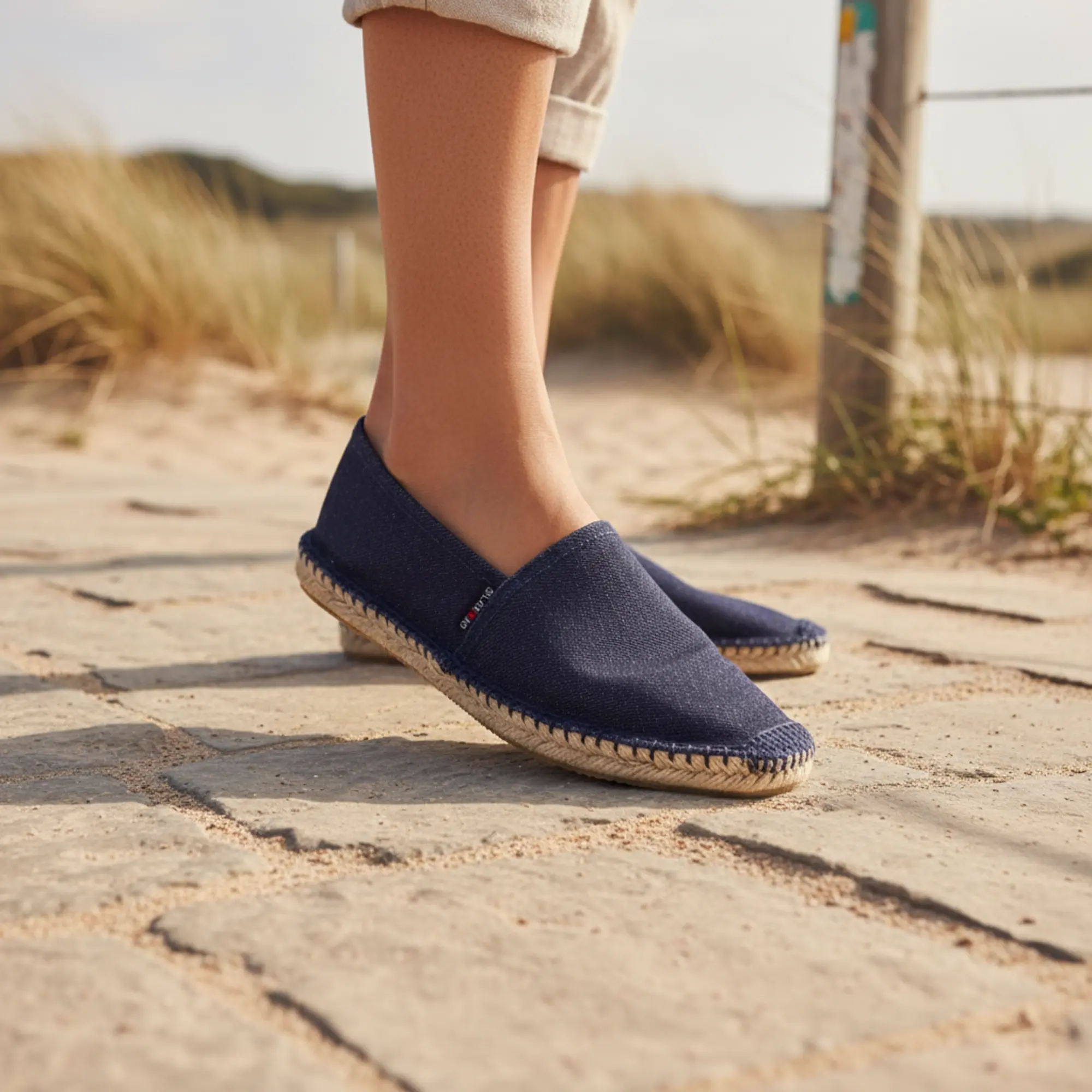 Person in Jeans-Espadrilles auf dem Strandweg.