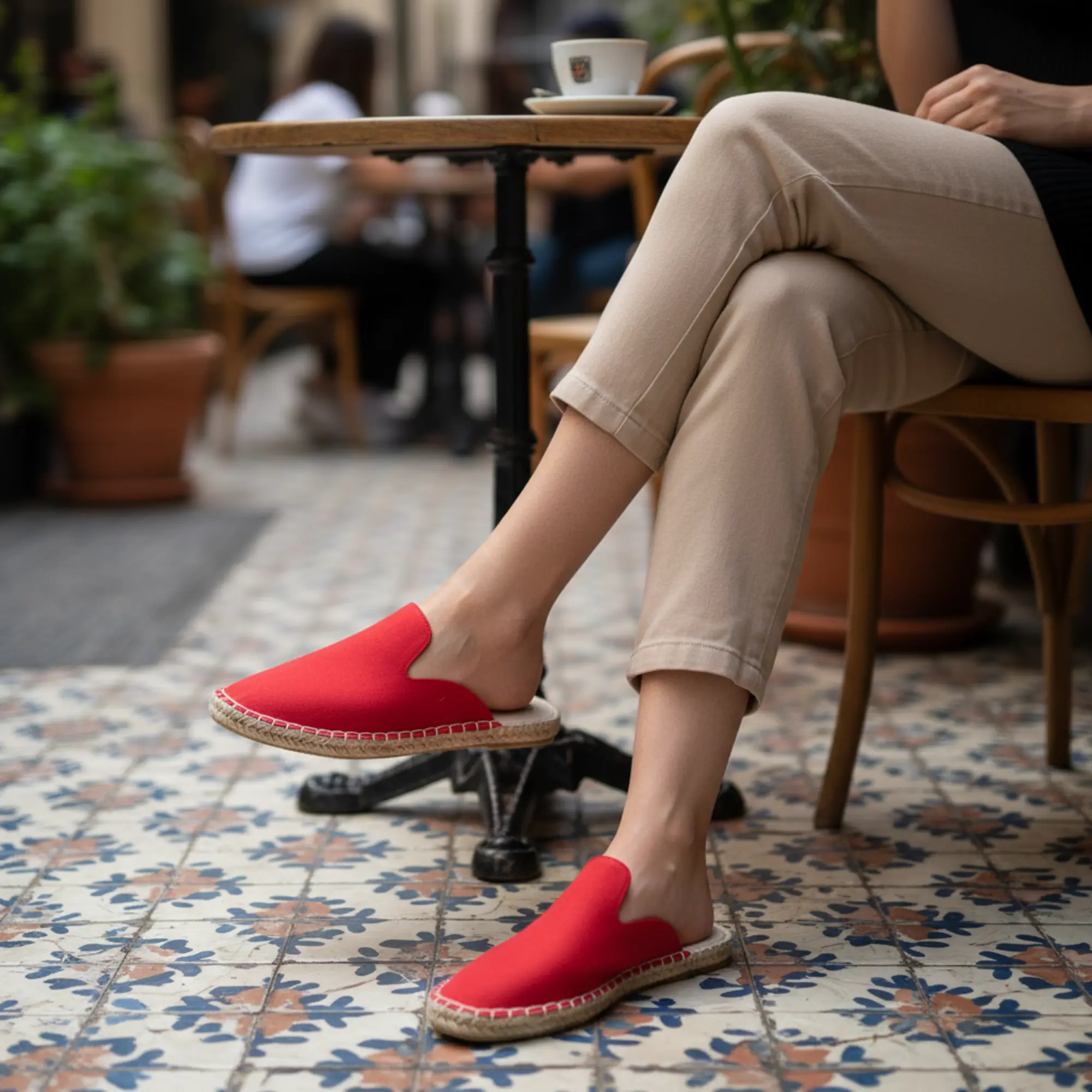 Frau in roten Espadrilles an einem Tisch in einem Straßencafé.